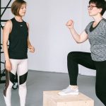 Fitness coach guides a woman in workout indoors. Focus on exercise and healthy lifestyle.