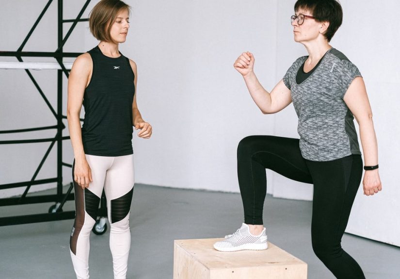 Fitness coach guides a woman in workout indoors. Focus on exercise and healthy lifestyle.